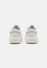 Sneaker bianche con finitura in pelle liscia; dotate di accenti in metallo dorato e suola testurizzata. Design elegante a scollatura sul tallone.