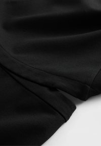 Melns audums ar gludu tekstūru, ar šuvi un nelielu krokām. Materiāls izskatās mīksts, bez redzamām rakstu zīmēm vai akcentiem.