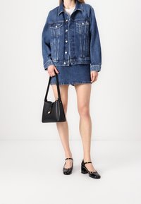 Denimjacka med knäppning fram, fickor, ihopparad med en denimkjol i mini-modell. Svart axelväska och glänsande svarta höga skor.