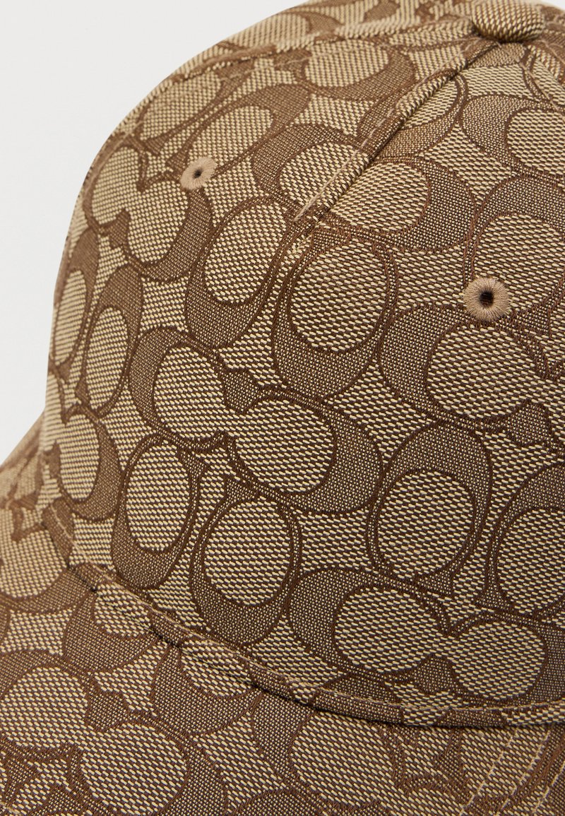 Bruine stoffen pet met een textuurpatroon van onderling verbonden cirkels, met een gestikte bovenkant en ventilatiegaatjes. Duurzaam ontwerp voor casual draagmode.