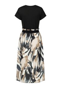 Haut noir à manches courtes relié à une jupe fluide avec des motifs abstraits beiges, noirs et blancs. Comprend une taille élastique.