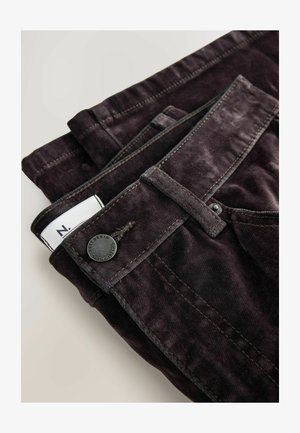 Donkerpaarse corduroy broek met een gestructureerde afwerking, voorzien van een knoopsluiting, riemlussen en een klein label met een witte streep.
