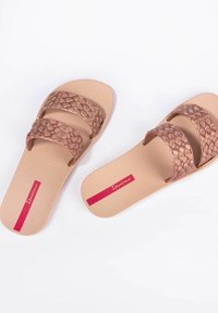 Sandalias de tiras trenzadas marrones con dos correas anchas, suela texturizada y un logo rosa en la plantilla.