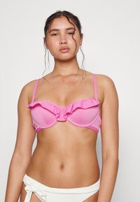Top de bikini rosa com borda em babados, suporte de aro, tecido texturizado e alças finas ajustáveis. Sem padrões ou acentos adicionais.