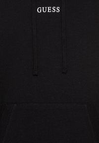 Black hoodie with a kangaroo pocket, drawstring hood, and white "GUESS" logo on the chest. Soft, cotton-blend fabric with ribbed cuffs.