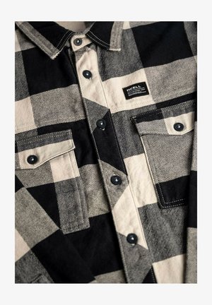 Black and white plaid shirt made of textured fabric featuring a button-up front, two chest pockets, and a small brand label.