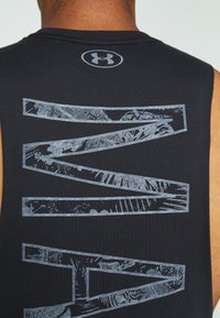 Personne musclée portant un débardeur noir Under Armour avec de grandes formes géométriques à motifs dans le dos.