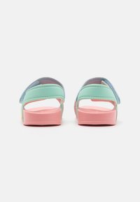 To par bagsandaler med mintgrønne og lyseblå stropper, lyserøde såler og en glat tekstur. De har et åbent design og justerbare stropper.