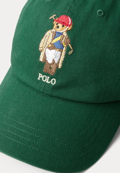 Πράσινο καπέλο μπέιζμπολ με κεντημένη αρκουδάκι σε ενδυμασία πόλο που κρατά ένα σφυρί, με το κείμενο "POLO" κεντημένο κάτω από το αρκουδάκι.