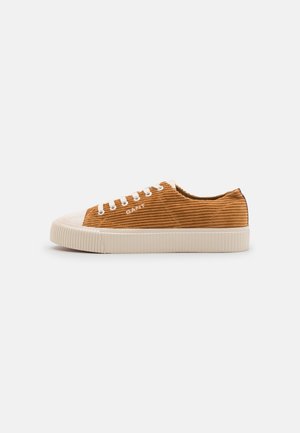 Niskie sneakersy z brązową cholewką z sztruksu, białą gumową podeszwą, białymi sznurowadłami i nazwą marki "GANT" po boku.