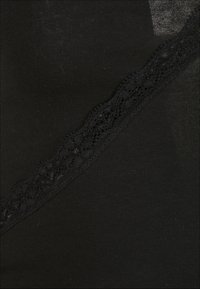 Černá tkanina s texturovaným krajkovým detailem podél jednoho okraje, s hladkým povrchem a mírným leskem v některých oblastech.