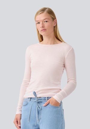Ljust rosa långärmad T-shirt med rund halsringning och figurnära design, parat med ljusblå jeans med dragsko i midjan.
