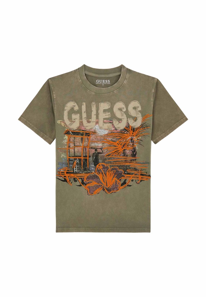 Olīvu zaļa T-krekls ar "GUESS" uzrakstu gaiši pelēkā krāsā, ar oranžiem ziedu un arhitektūras grafikas elementiem. Īsas piedurknes un apaļa kakla izgriezums.