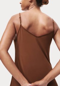 Abito marrone senza maniche con scollo a V e spalline regolabili, caratterizzato da una texture liscia e opaca e da dettagli sottili sulla minuteria delle spalline.