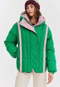 Zelená vatovaná bunda s ružovým podšitím, vybavená vysokým golierom, patentkami a vertikálnou rebrovanou textúrou. S kapucňou a elastickými manžetami.