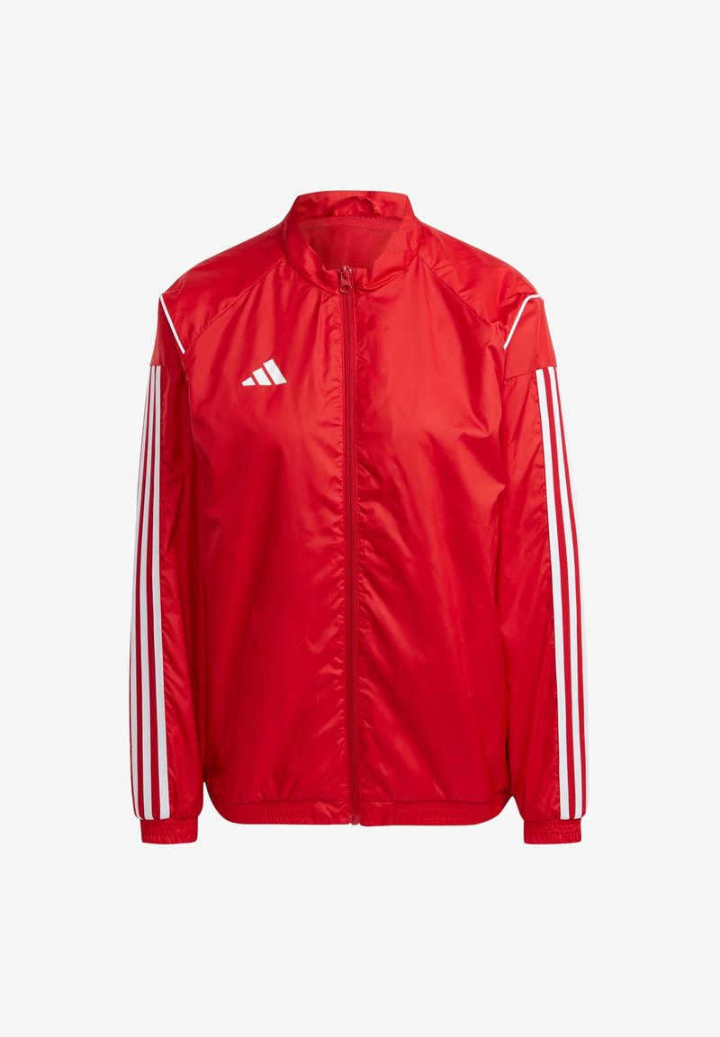 Veste de sport rouge avec un design à trois bandes blanches sur les manches, une fermeture éclair à l'avant et un petit logo Adidas blanc sur la poitrine gauche.