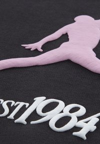 Tessuto nero con grafica silhouette rosa e testo ricamato bianco "est 1984", dalla texture liscia e cuciture a contrasto.