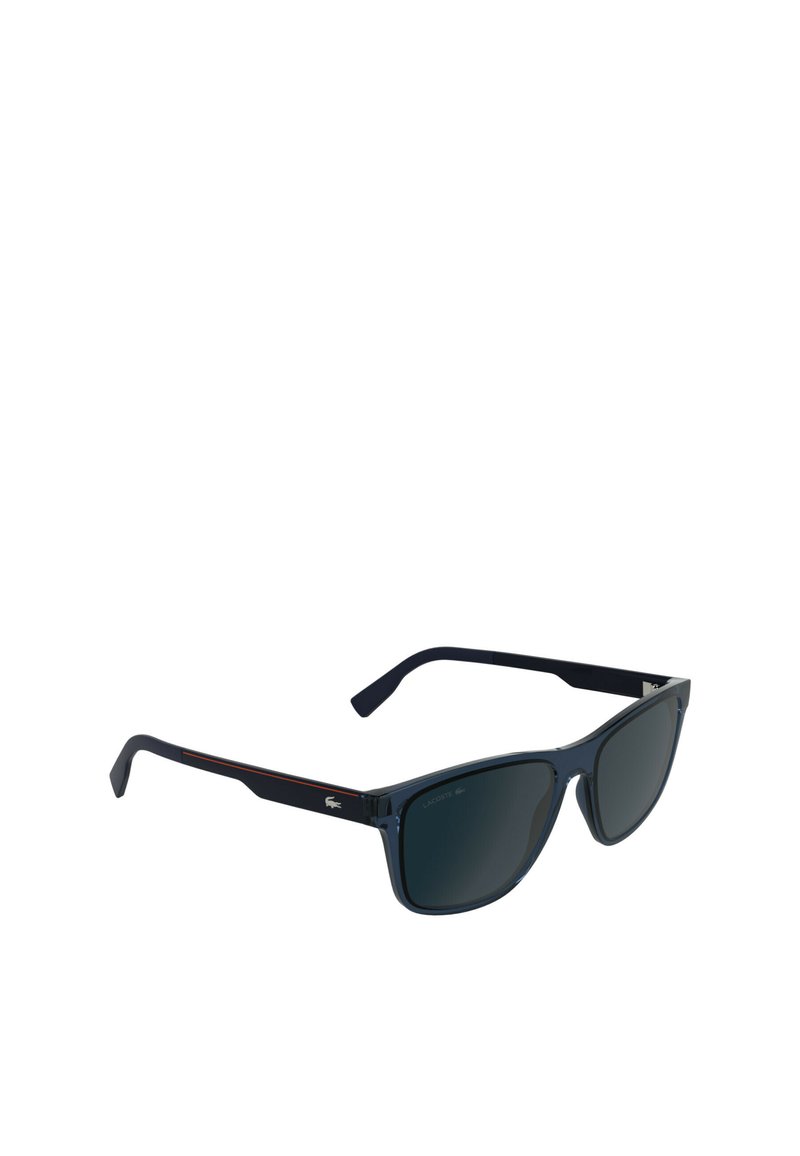 Lunettes de soleil avec une monture en plastique bleu foncé, des verres sombres, une forme triangulaire et des accents rouges subtils sur les branches. Présente un logo près de la tempe.