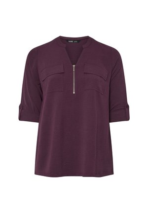 Top viola con scollatura a V, zip frontale e due tasche sul petto. Il materiale ha una finitura tessurizzata, con maniche arrotolate.