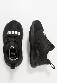 Black athletic shoes with mesh upper, padded collar, and rubber sole. Features a wide strap with "PUMA" logo and lightweight design.