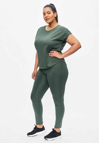 Green athletic wear set featuring a short-sleeve top and fitted leggings. Smooth, stretchy fabric with a round neck and subtle seams.