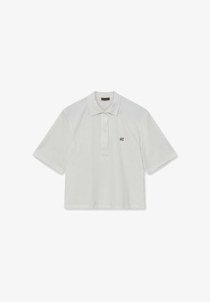 Fehér pamut pólóing, galléros nyakkal, rövid ujjakkal és egy zsebből áll, amelyen egy kis hímzett logó található a bal mellen.