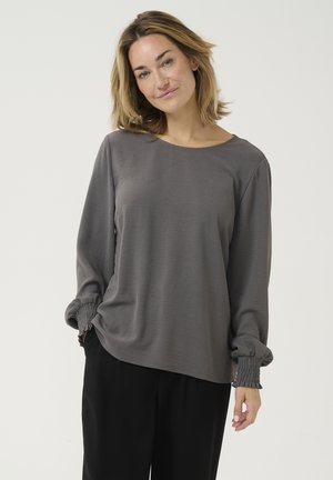 T-shirt gris à manches longues avec un col rond et des poignets froncés, fabriqué dans un tissu léger et texturé, avec une coupe décontractée.