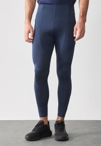 Tengeri kék sportleggings, rugalmas anyagból, magas derékkal, varrás nélküli oldalakkal és megkönnyített lábakkal. Fekete sportcipők included.