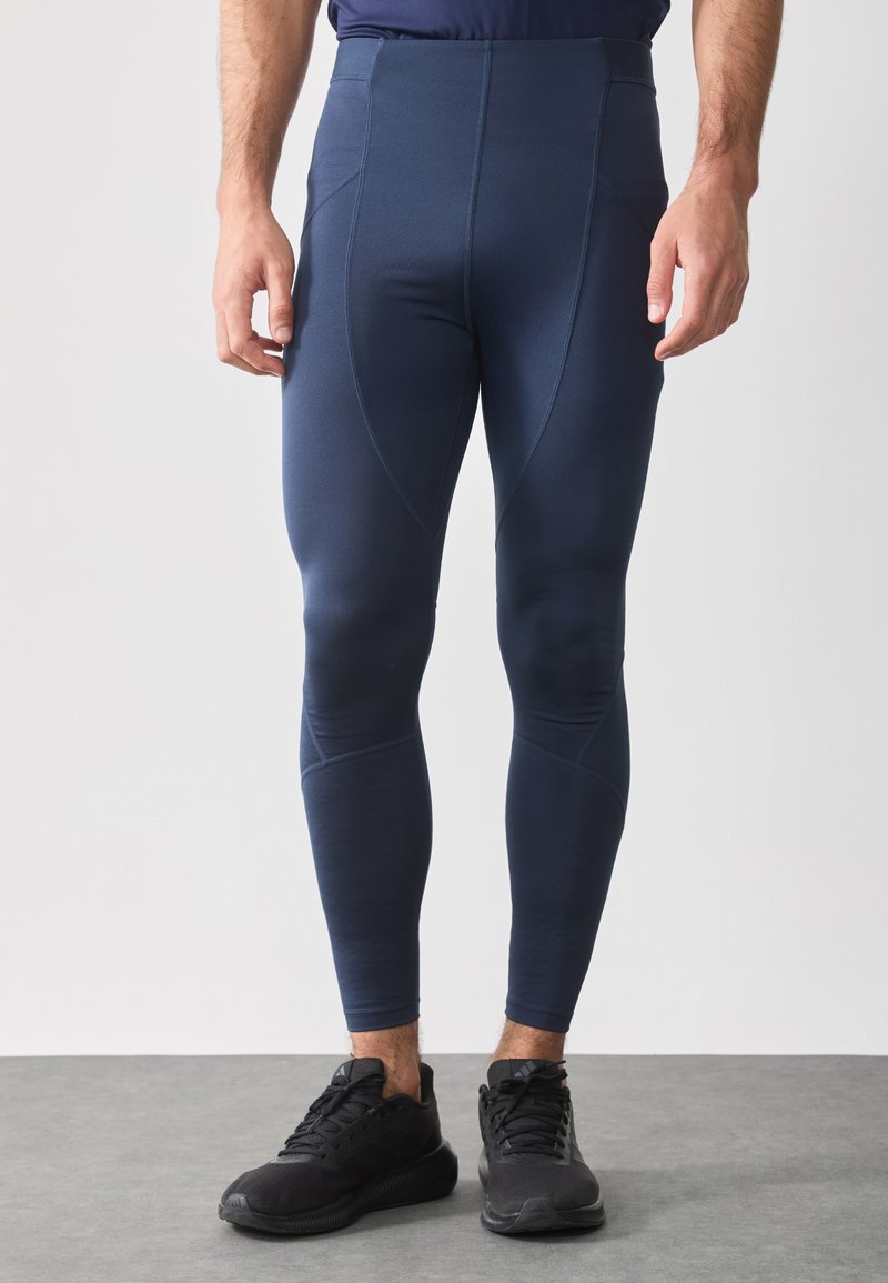 Tengeri kék sportleggings, rugalmas anyagból, magas derékkal, varrás nélküli oldalakkal és megkönnyített lábakkal. Fekete sportcipők included.