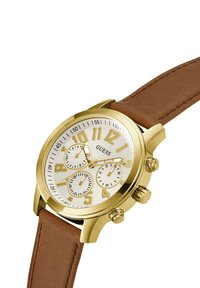 Orologio cronografo color oro con quadrante bianco, grandi numeri e tre sottoquadranti. Cinturino in pelle marrone con finitura testurizzata.