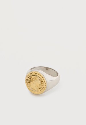 Silver ring featuring a round gold coin design with an embossed profile of a head and surrounding text on a plain background.