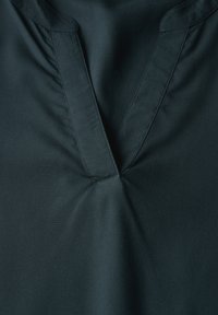 Top in tessuto nero con scollatura a V e delicate arricciature nella parte anteriore, caratterizzato da una superficie liscia. Le cuciture pulite evidenziano il design.