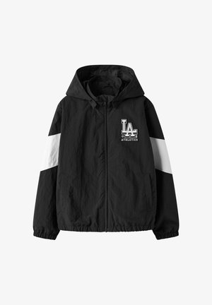 Crna sportska jakna s kapuljačom, bijelom prugom na rukavima i logotipom "LA Athletics" na lijevoj strani prsa, prednji zatvarač i bočni džepovi.
