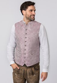 Traditionelle Weste im hellpinkfarbenen Paisleymuster, mit Metallknöpfen, einem kragenlosen Design und zwei vorderen Taschen. Darunter ein weißes Langarmhemd.