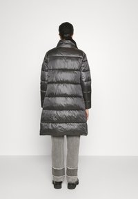 Černý prošívaný kabát s vysokým límcem, s elegantní lesklou texturou. Design zahrnuje horizontální prošívané části.