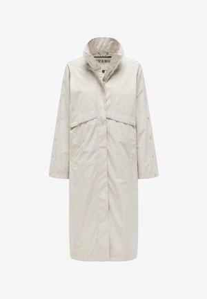 Lang beige regnfrakk med høy krage, frontlommer og trykknapper langs ermene og frontlukking.