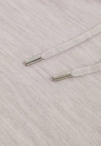 Jasnoszara tkanina z teksturowaną powierzchnią. Posiada sznurki z metalowymi końcówkami oznaczone "REISS". Gładki, minimalistyczny design.
