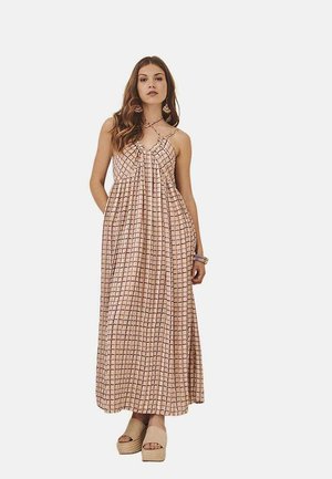 Vestido maxi de color rosa claro con un patrón de cuadrícula, que presenta tirantes ajustables y un ajuste holgado. Se lleva con zapatos de plataforma beige.