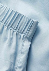 Light blue fabric with elasticated cuff detail and visible stitching on a soft, smooth textile surface.