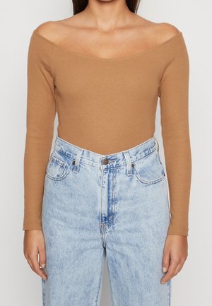 Brown ribbed long-sleeve top with an off-shoulder design, paired with light blue high-waisted jeans featuring a faded pattern and five pockets.