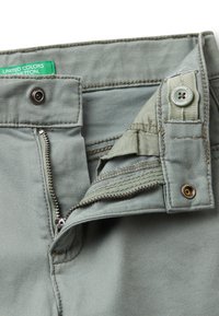 Světle zelené bavlněné kalhoty s kovovým zipem, zapínáním na knoflík a vnitřním textilním detailem. Mají tónové švy a štítek.