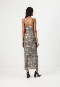 Maxi dress in a snake print design, featuring thin straps, soft texture, and a fitted silhouette. Paired with black block-heeled shoes.