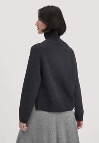 Dunkelgrauer Rollkragenpullover mit geripptem Saum und Bündchen, der aus einem strukturierten Stoff gefertigt ist und Raglanärmel für eine lässige Passform bietet.