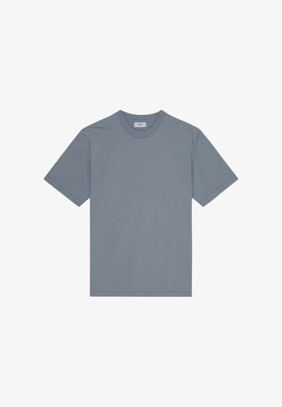 T-shirt uni à manches courtes et col rond de couleur bleu-gris atténuée, posé à plat avec coutures visibles et étiquette au niveau du col.