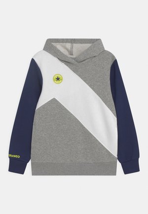 Sudadera con capucha en gris y azul marino, con una franja diagonal blanca, que presenta un logo circular y un detalle en texto verde en la manga izquierda.