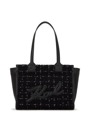 Sac fourre-tout noir avec un corps en tissu texturé affichant un motif tissé, des accents en cuir noir lisse et un logo en relief bien en vue.