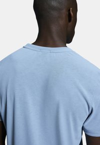 Light blue cotton t-shirt featuring a crew neckline and short sleeves, with a smooth texture and minimal stitching detail at the back.