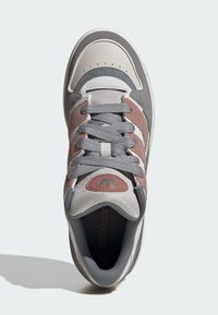 Gray and beige athletic shoe with suede and mesh materials, featuring three stripes, round logo, and textured detailing on the upper.
