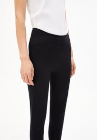 Svarta leggings med hög midja, tillverkade av mjukt stretchtyg. Har en kroppsnära passform och detaljer i sido sömmen.