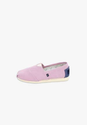 Zapato casual tipo slip-on con parte superior de tela color lila claro, suela blanca y parche azul oscuro en el talón, visto de lado sobre fondo blanco.